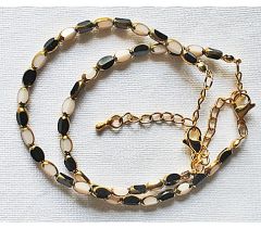 Armband zwarte en witte kralen 5x3mm met goudkleurige rand